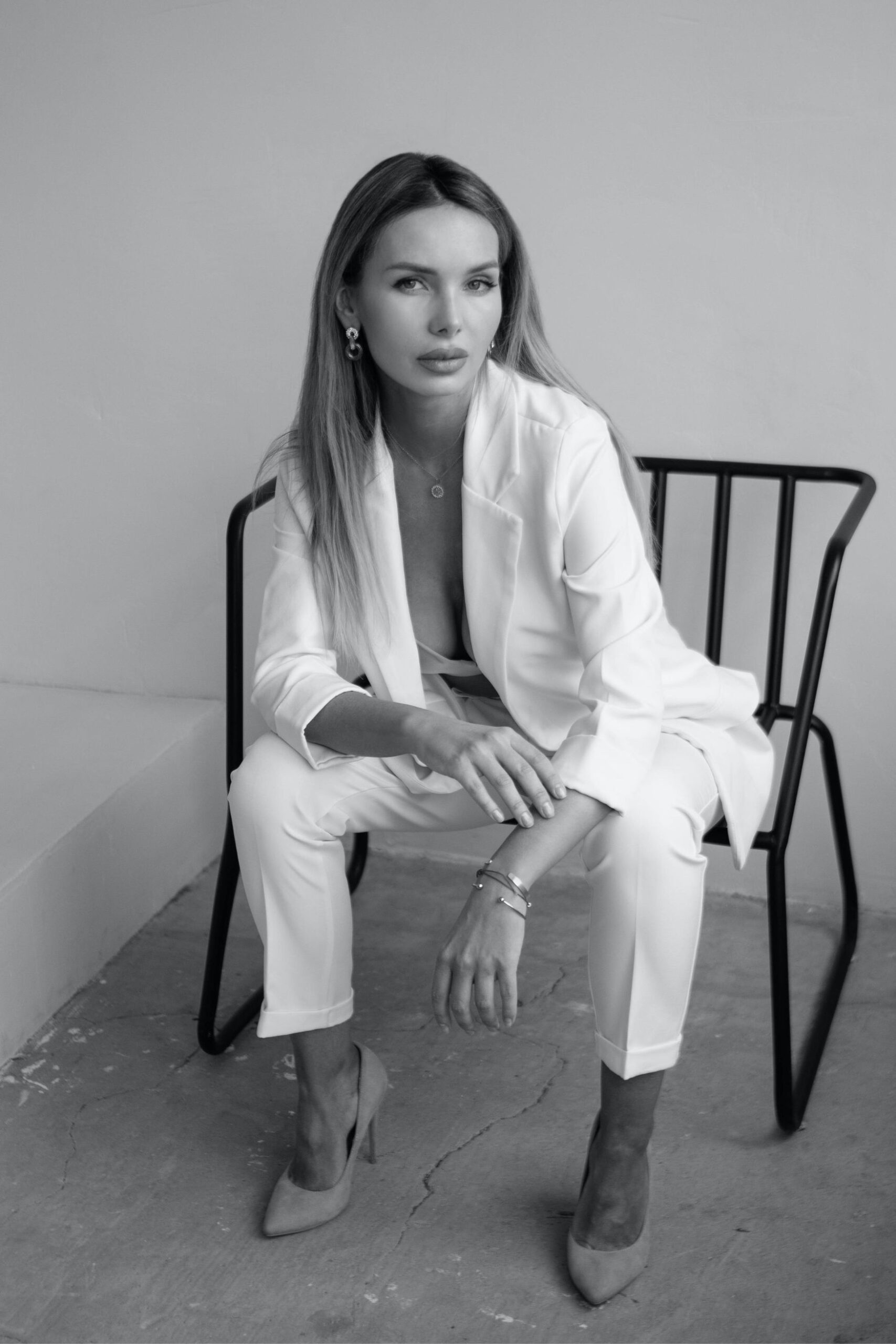 Female Founder sitting in a power pose wearing a white suit and high heels
